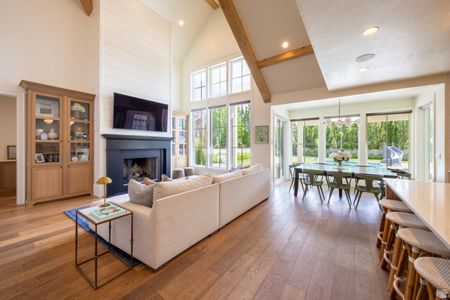 630 East Center Street Alpine, UT 84004 - Photo 33 of 115 Spacious living area featuring wood-finish flooring, a vaulted ceiling with exposed wood beams, and a dark mantel over a fireplace