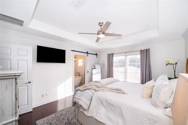 a bedroom with a bed a tv and wooden floor