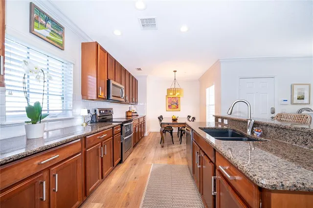 a kitchen with stainless steel appliances granite countertop a sink a stove top oven a counter space and cabinets