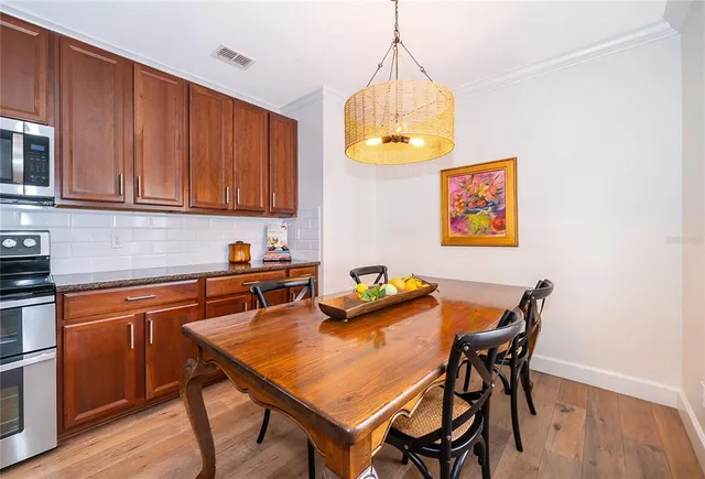 a kitchen with stainless steel appliances granite countertop a sink a stove a dining table and chairs with wooden floor