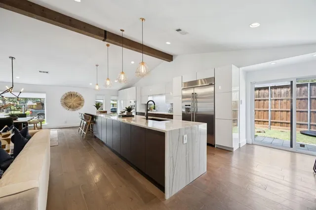 a large kitchen with stainless steel appliances kitchen island a large counter top and a wooden floors
