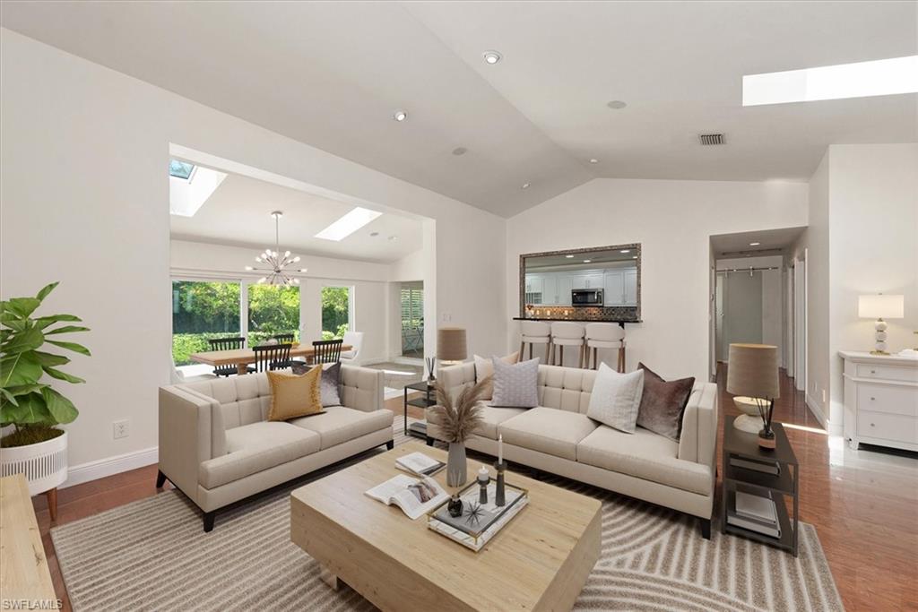 2252 Royal Lane Naples, FL 34112 - Photo 2 of 42 Living area featuring skylights, a chandelier, lofted ceiling, and wood floors. Room is staged
