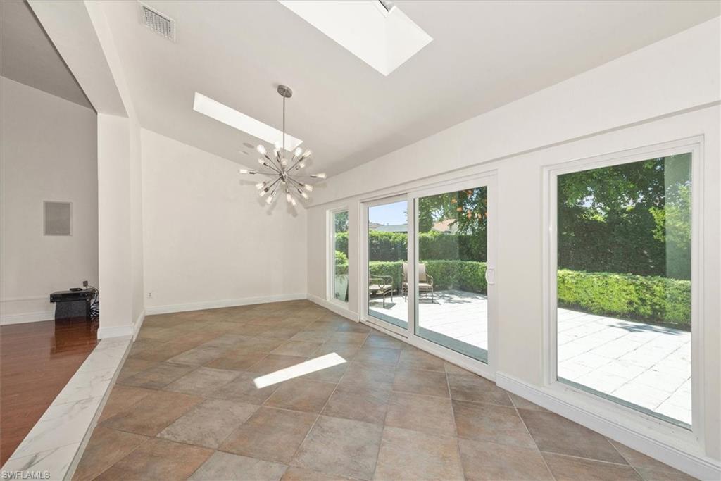 2252 Royal Lane Naples, FL 34112 - Photo 24 of 42 Unfurnished dining area featuring 2 skylights, vaulted ceiling, striking chandelier and tile floors. Overlooks rear patio