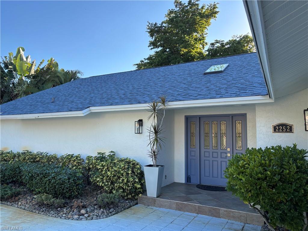 2252 Royal Lane Naples, FL 34112 - Photo 6 of 42 View of exterior entry with NEW roof and gutters, skylight and stucco siding
