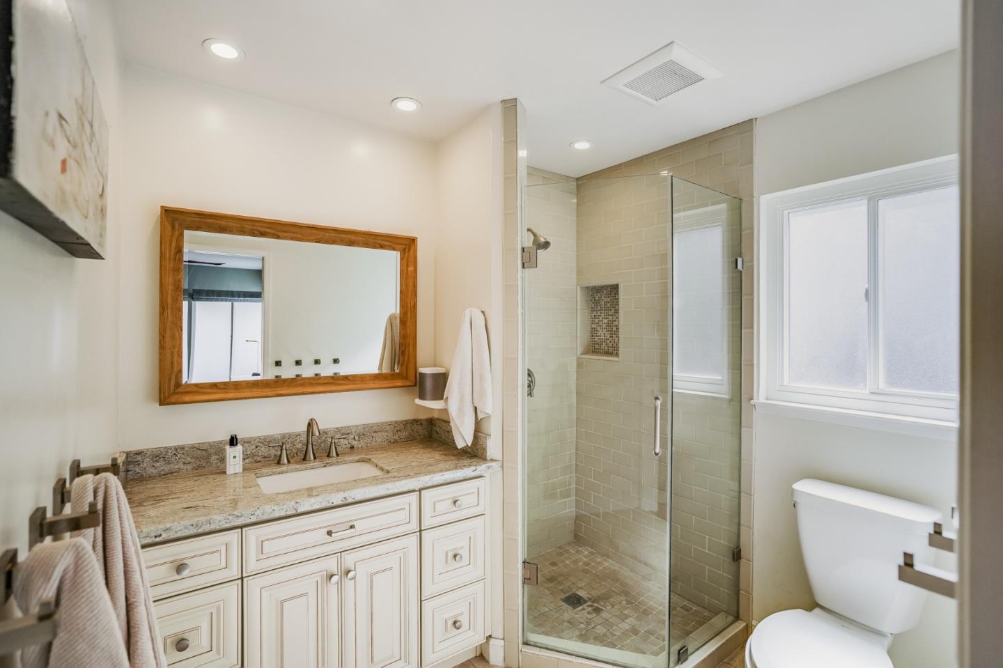 775 Pico Avenue San Mateo, CA 94403 - Photo 41 of 66 a bathroom with a granite countertop sink toilet a mirror a vanity and shower