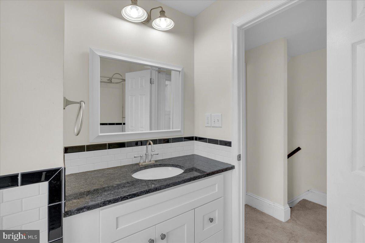 45 Broad Street Mount Holly, NJ 08060 - Photo 36 of 58 a bathroom with a granite countertop sink and a mirror