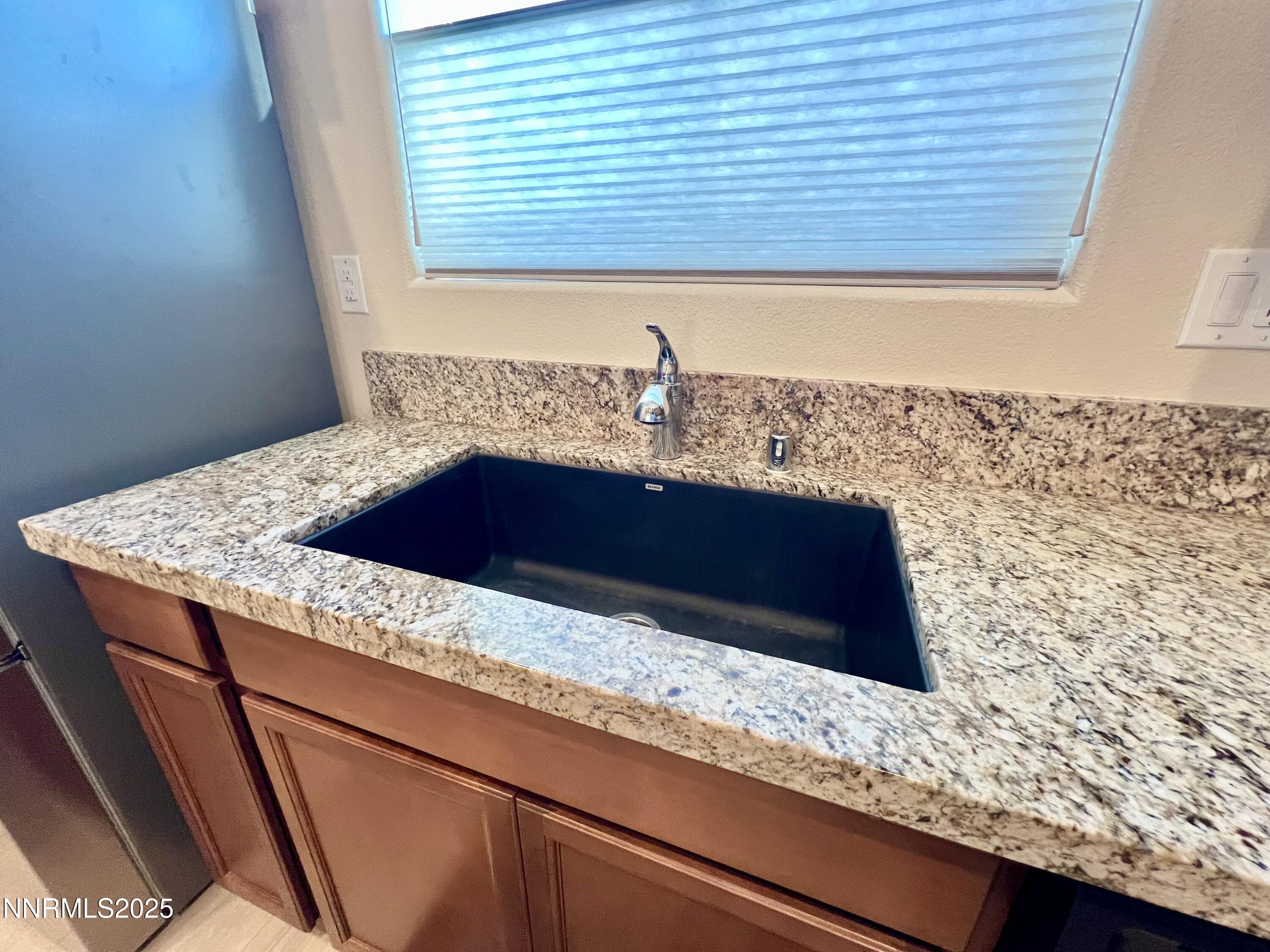 4969 Cavestone Road Sun Valley, NV 89433 - Photo 11 of 40 a bathroom with a granite countertop sink and a large mirror