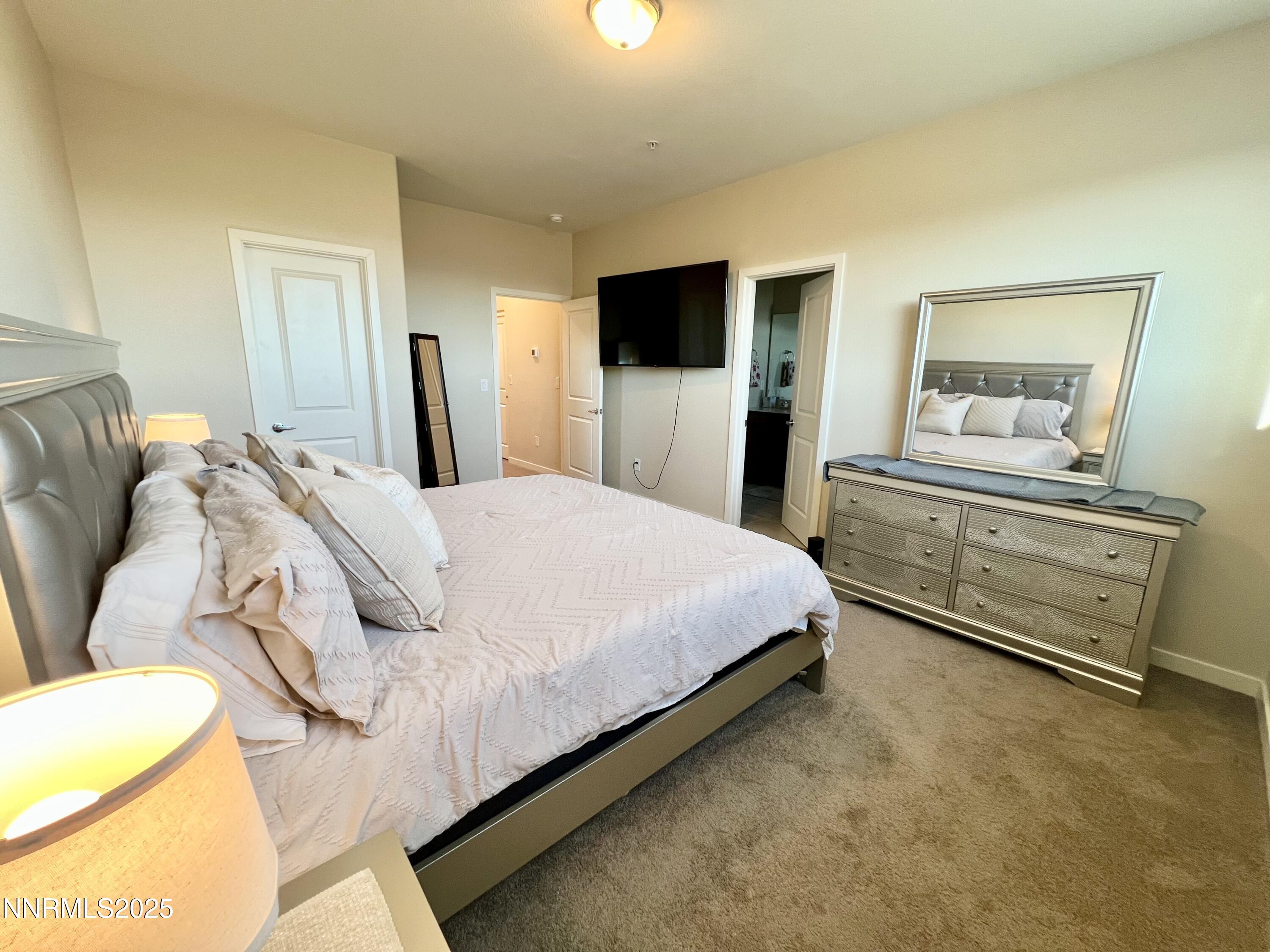 4969 Cavestone Road Sun Valley, NV 89433 - Photo 32 of 40 a spacious bedroom with a bed and a flat screen tv