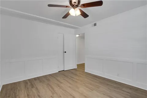an empty room with wooden floor ceiling fan and window
