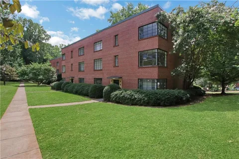 a view of a building next to a big yard and large trees
