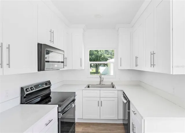 a kitchen with white cabinets sink and stove