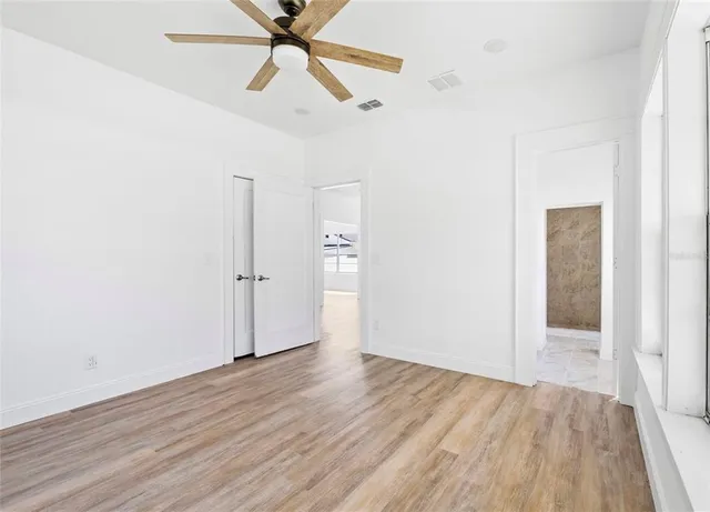 an empty room with wooden floor a ceiling fan and closet