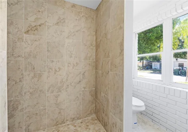 a bathroom with a granite countertop shower a toilet and a shower