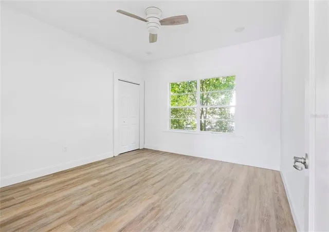 an empty room with wooden floor and windows
