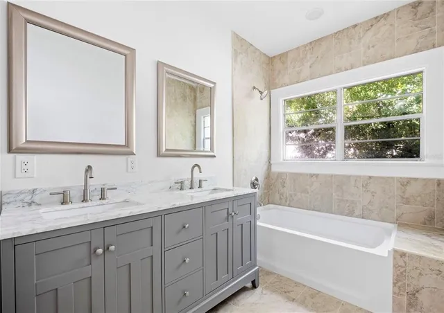 a bathroom with a tub a sink and a window