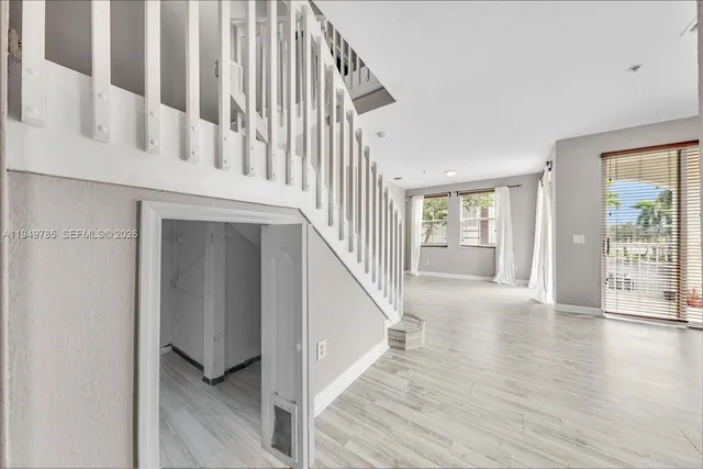 a view of an entryway with wooden floor leading to a furnished livingroom and windows