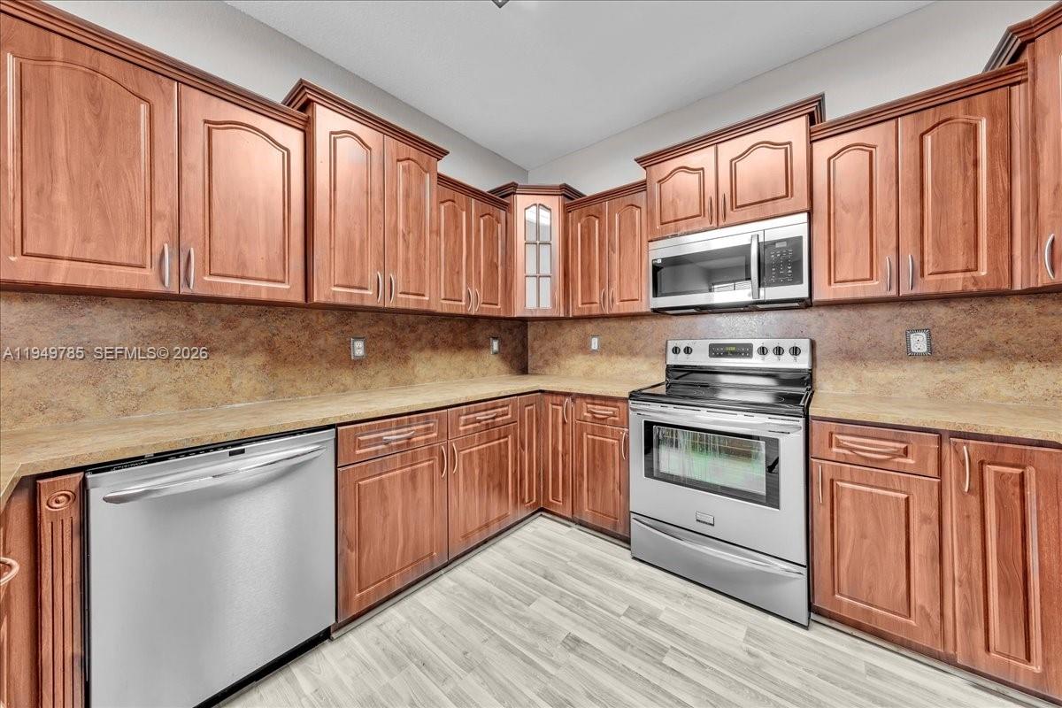 4341 Southwest 160th Avenue, Unit 201 Miramar, FL 33027 - Photo 22 of 53 a kitchen with granite countertop wooden cabinets and stainless steel appliances