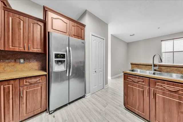 a kitchen with kitchen island granite countertop wooden cabinets a sink and stainless steel appliances