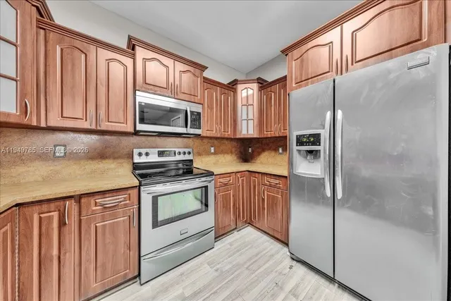 a kitchen with stainless steel appliances granite countertop a refrigerator and a stove top oven
