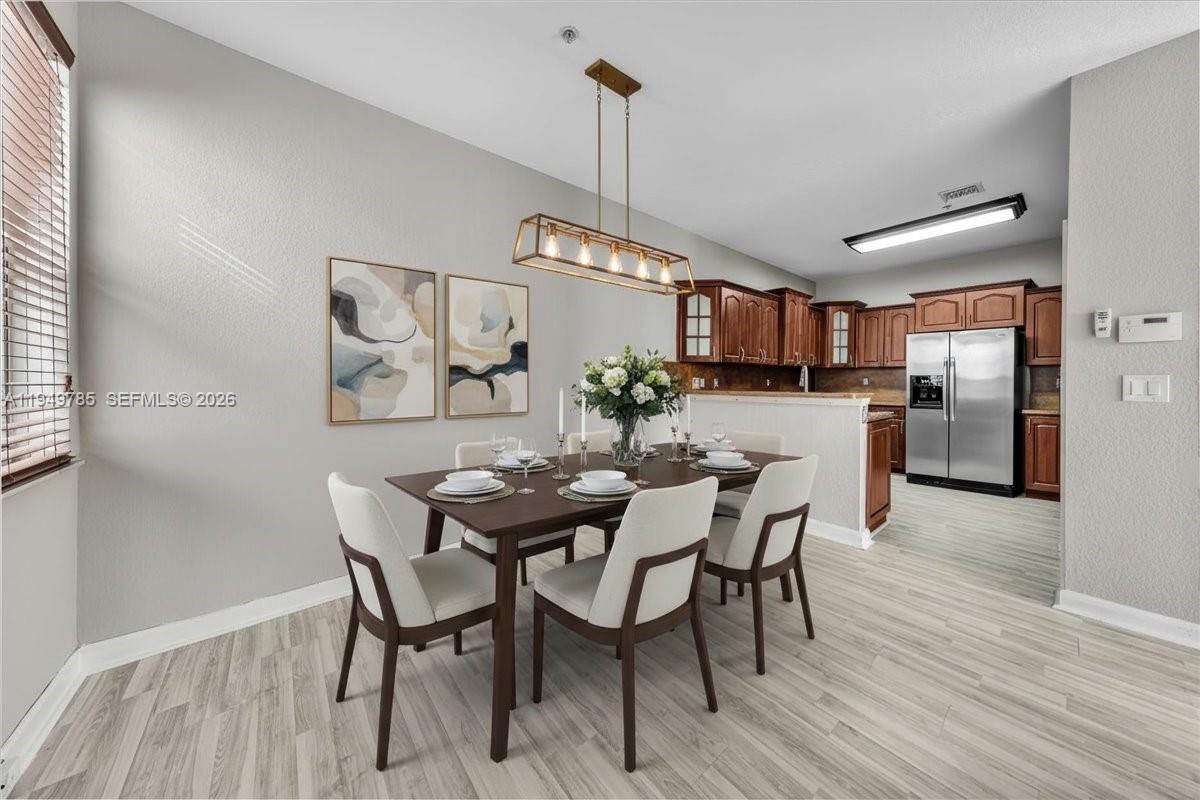 4341 Southwest 160th Avenue, Unit 201 Miramar, FL 33027 - Photo 4 of 53 a view of a dining room with furniture a chandelier and wooden floor