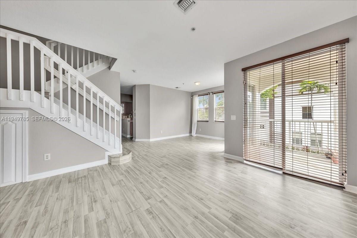 4341 Southwest 160th Avenue, Unit 201 Miramar, FL 33027 - Photo 9 of 53 a view of an empty room with wooden floor and a window