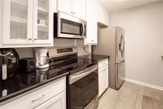 a kitchen with stainless steel appliances granite countertop a refrigerator and a stove top oven