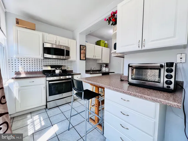 a kitchen with stainless steel appliances kitchen island granite countertop a stove a sink and a microwave
