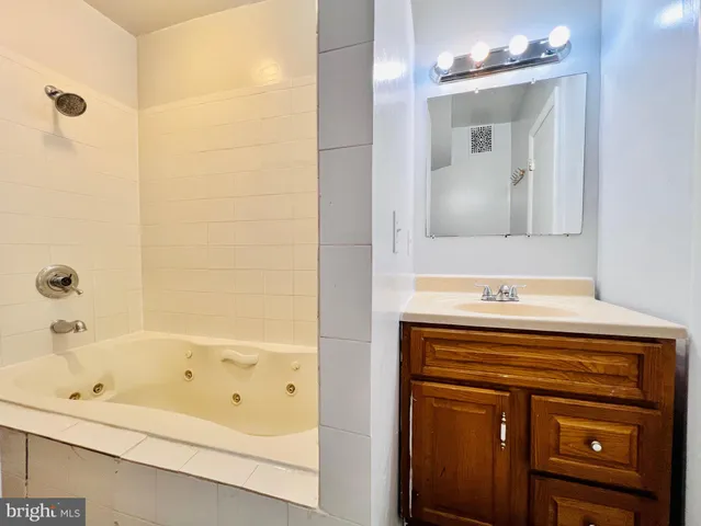 a bathroom with a bathtub sink vanity and mirror