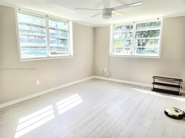 a view of empty room with wooden floor and fan