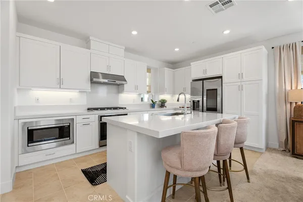 a kitchen with a sink a stove a refrigerator and white cabinets