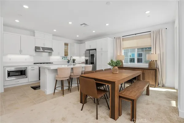a kitchen with stainless steel appliances granite countertop a table chairs sink refrigerator and cabinets