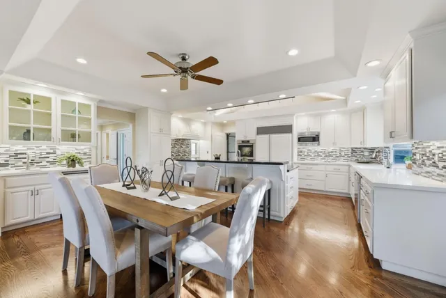 a dining room with stainless steel appliances kitchen island granite countertop a dining table chairs and a refrigerator