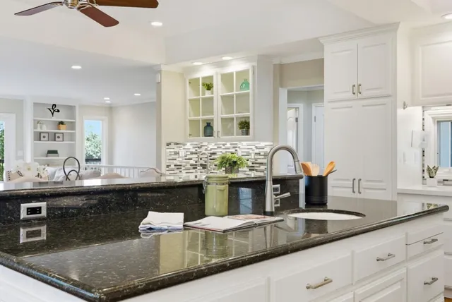 a kitchen with granite countertop a stove and white cabinets