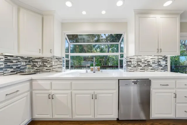 a kitchen with white cabinets and sink