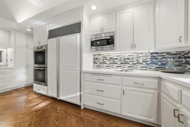 a kitchen with white cabinets and stainless steel appliances