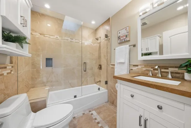 a bathroom with a granite countertop sink toilet tub and shower