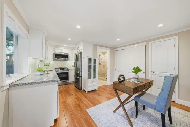 a living room with stainless steel appliances kitchen island granite countertop furniture wooden floor and a kitchen view