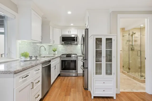 a kitchen with stainless steel appliances granite countertop a stove top oven a sink and a granite counter tops with wooden floors