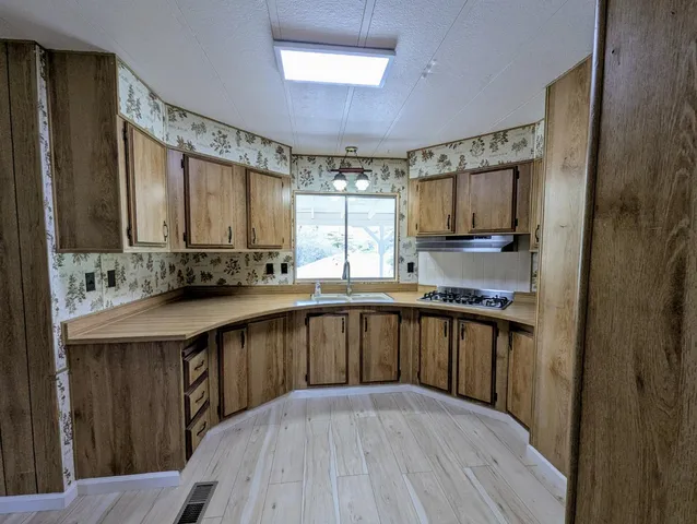 a kitchen with stainless steel appliances granite countertop a sink a stove a refrigerator cabinets and a microwave