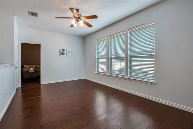 a view of an empty room with a window and wooden floor