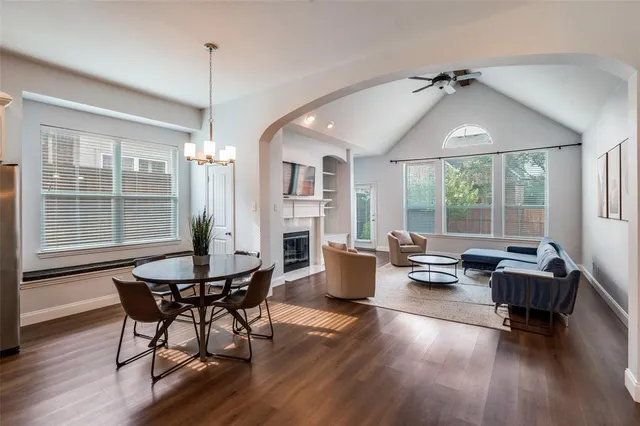 a dining room with wooden floor a chandelier a glass table and chairs