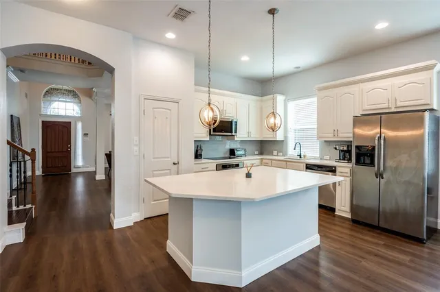 a large kitchen with a center island wooden floor stainless steel appliances and a center island