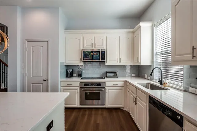 a kitchen with white cabinets sink and stainless steel appliances