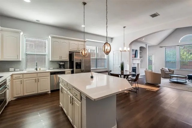 a large kitchen with kitchen island a white cabinets and wooden floor