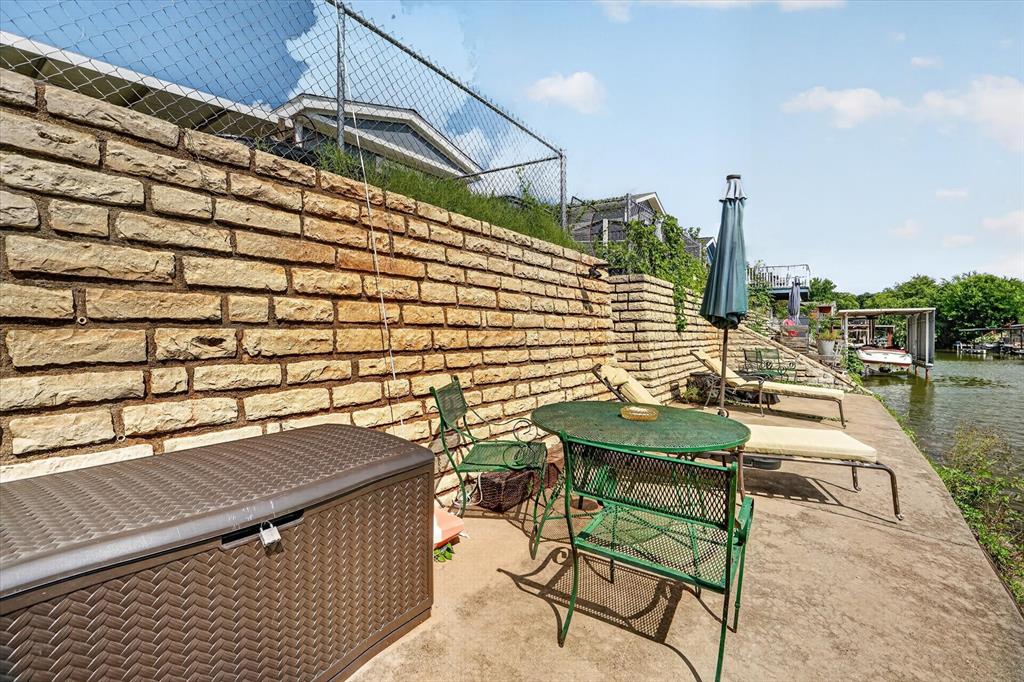 6602 Ashley Court Granbury, TX 76049 - Photo 28 of 35 Waterside patio featuring a stone retaining wall and a concrete surface