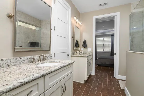 a en suite bathroom with a granite countertop sink and a mirror