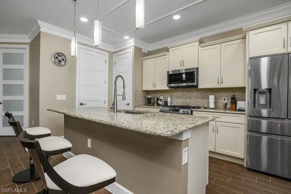 a kitchen with stainless steel appliances granite countertop a sink a stove a refrigerator cabinets and a dining table with wooden floor