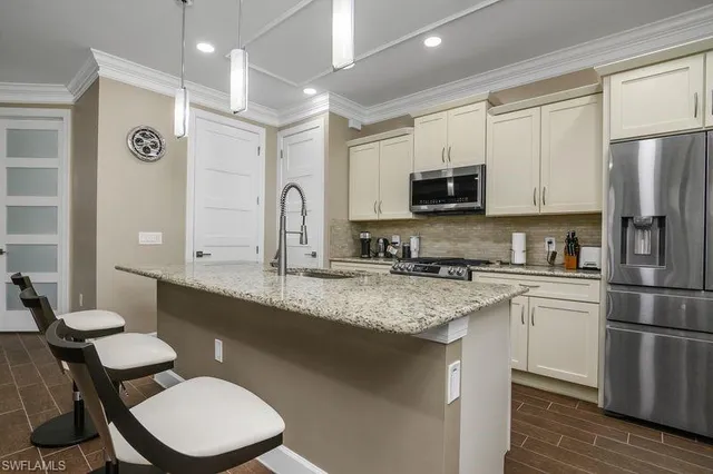 a kitchen with stainless steel appliances granite countertop a sink a stove a refrigerator cabinets and a dining table with wooden floor