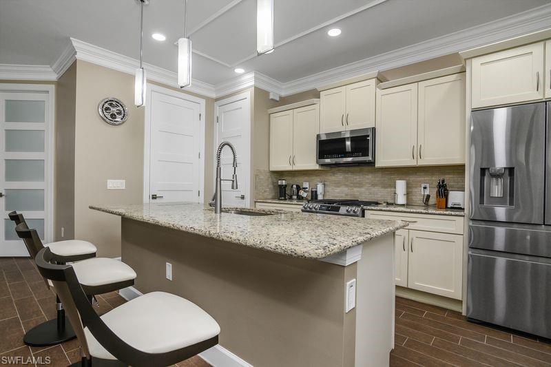 16309 Winfield Lane Naples, FL 34110 - Photo 5 of 36 a kitchen with stainless steel appliances granite countertop a sink a stove a refrigerator cabinets and a dining table with wooden floor
