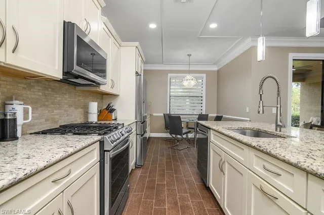 a kitchen with granite countertop stainless steel appliances a sink stove top oven and cabinets